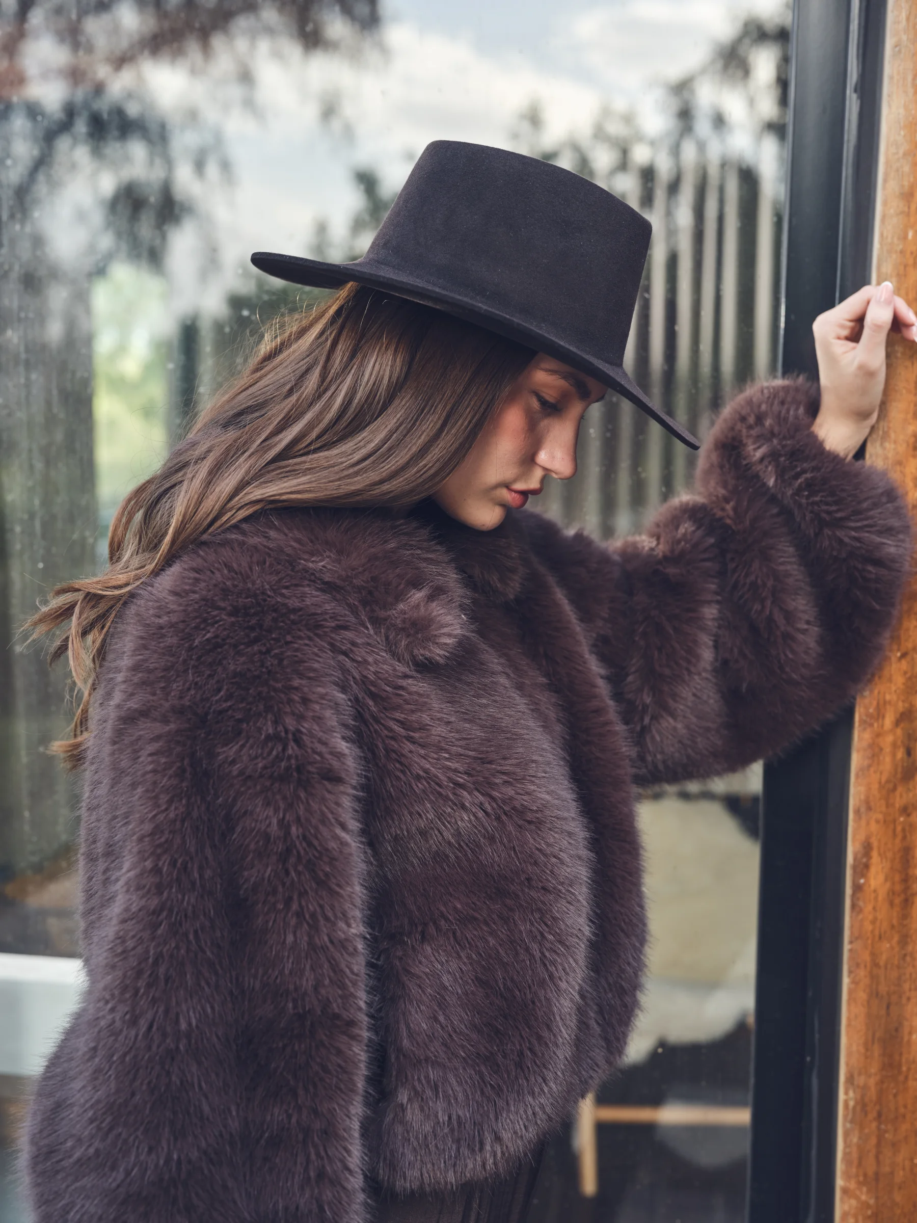 Mujer con sombrero Casa Sombra junto a una ventana